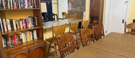 Un comedor con una larga mesa de madera y sillas, rodeado de estanterías llenas de libros.