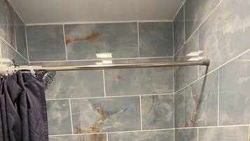 Ein Duschbereich mit gefliesten Wänden, einer Duschkabine und einer Toilette.