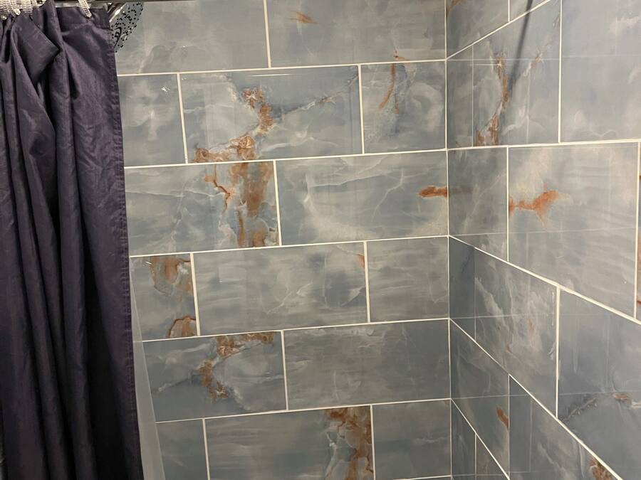 Ein Duschbereich mit gefliesten Wänden, einer Duschkabine und einer Toilette.