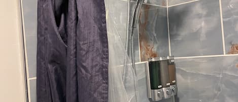 Ducha con cabezal de ducha de mano, barra para toallas y calentador de agua instalado en la pared.