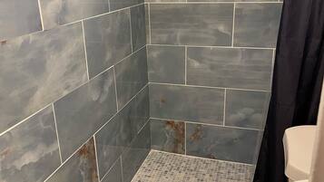 A bathroom with a shower, tiled walls, and a toilet.