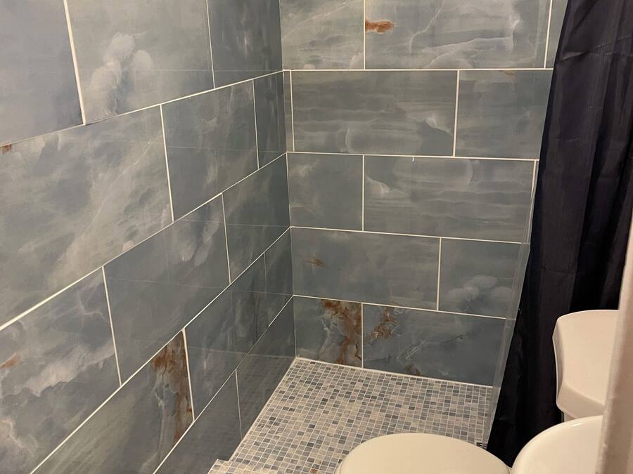 A bathroom with a shower, tiled walls, and a toilet.