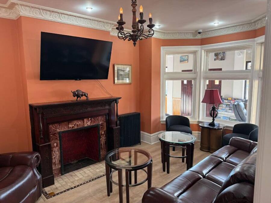 A living room with a fireplace, leather sofa, and a television mounted on the wall.