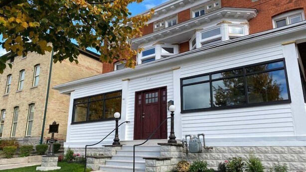 A two-story building with a white exterior, a red door, and large windows. - Buffalo Guesthouse (Buffalo)