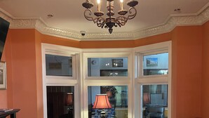 A living room with a fireplace, a chandelier, leather sofas, and a glass coffee table. - Buffalo Guesthouse (Buffalo)