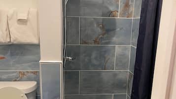Un bagno con doccia, WC e pareti piastrellate.