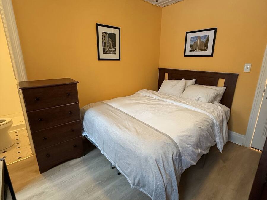 A bedroom with a bed, dresser, and ceiling with decorative elements.