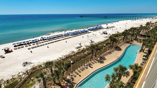 A beach resort with a swimming pool, beach umbrellas, and a pier. - ☀️Panoramic Gulf and Pool Views-Steps to Beach-Calypso 1-1709☀️ (Panama City Beach)