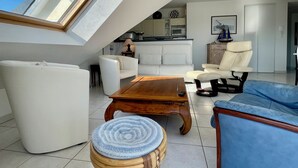 A modern living room with a high ceiling, a skylight, a sofa, a coffee table, and a blue armchair.