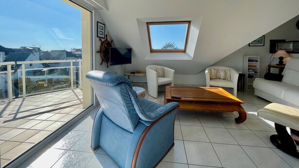 A modern living room with a large window, a television, and a cozy seating area.