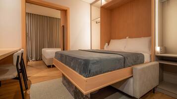 A modern hotel room with a wooden bed, a desk, and a chair.