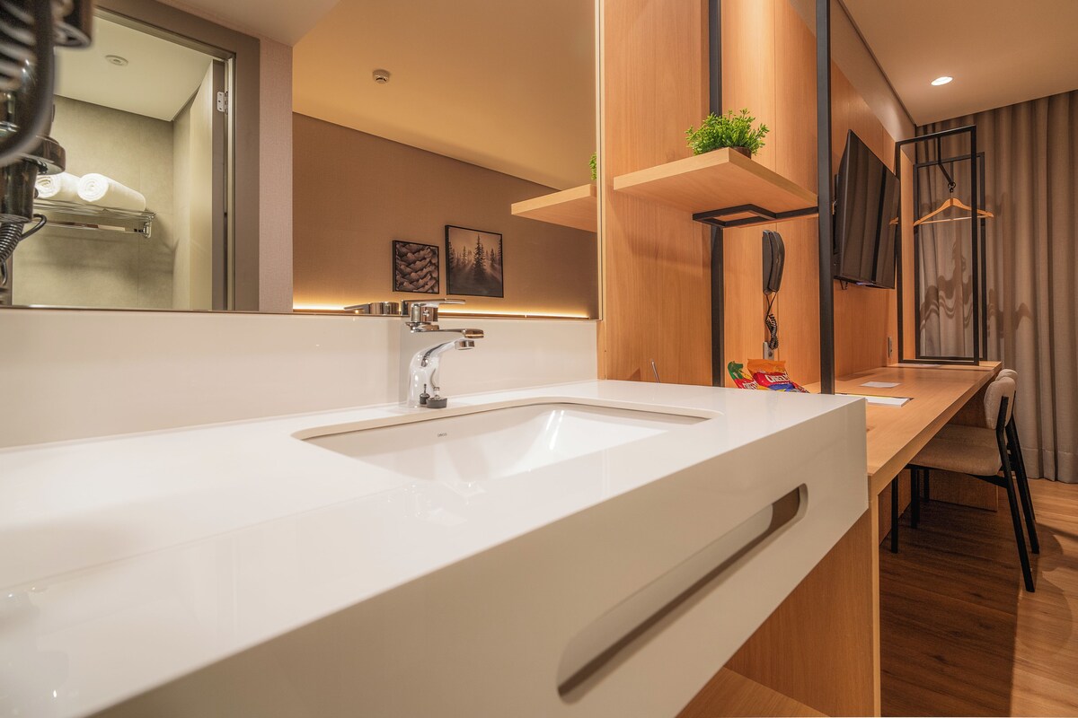 A modern bathroom with a large white sink, a mirror, and a wooden vanity.