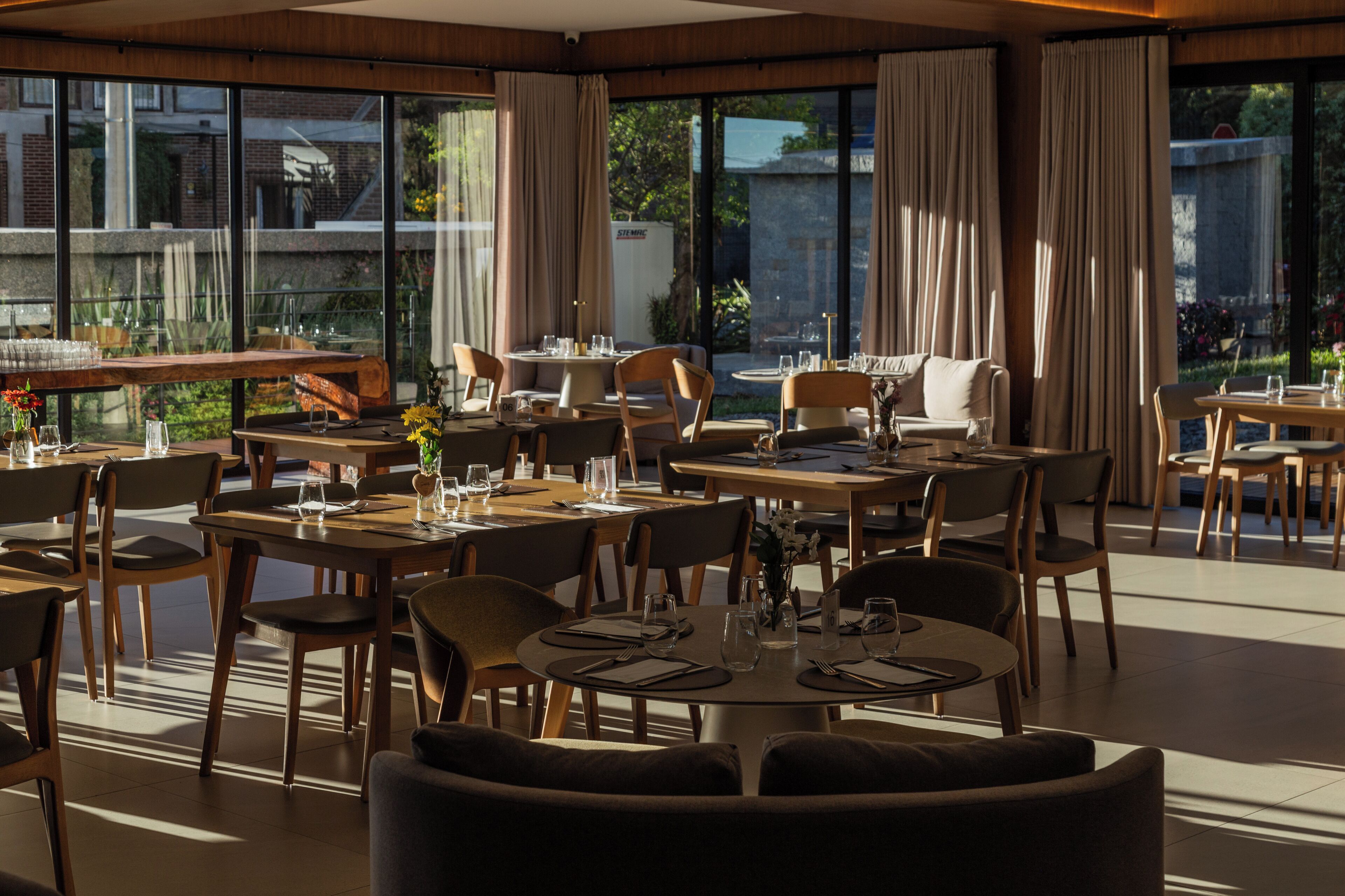 A restaurant with multiple tables and chairs, large windows, and a view of the outdoors.