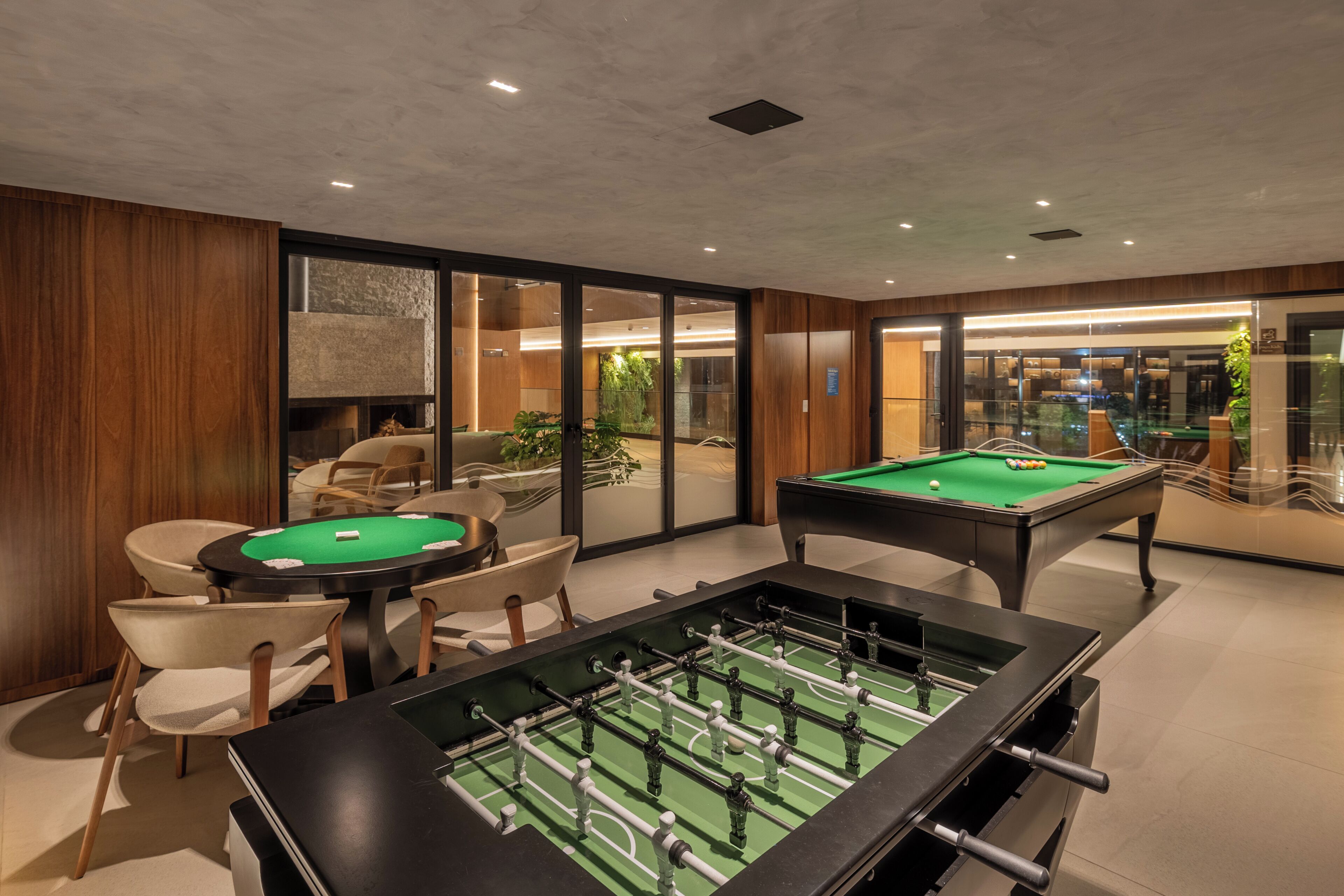 A room with a pool table, a foosball table, and a billiards table.