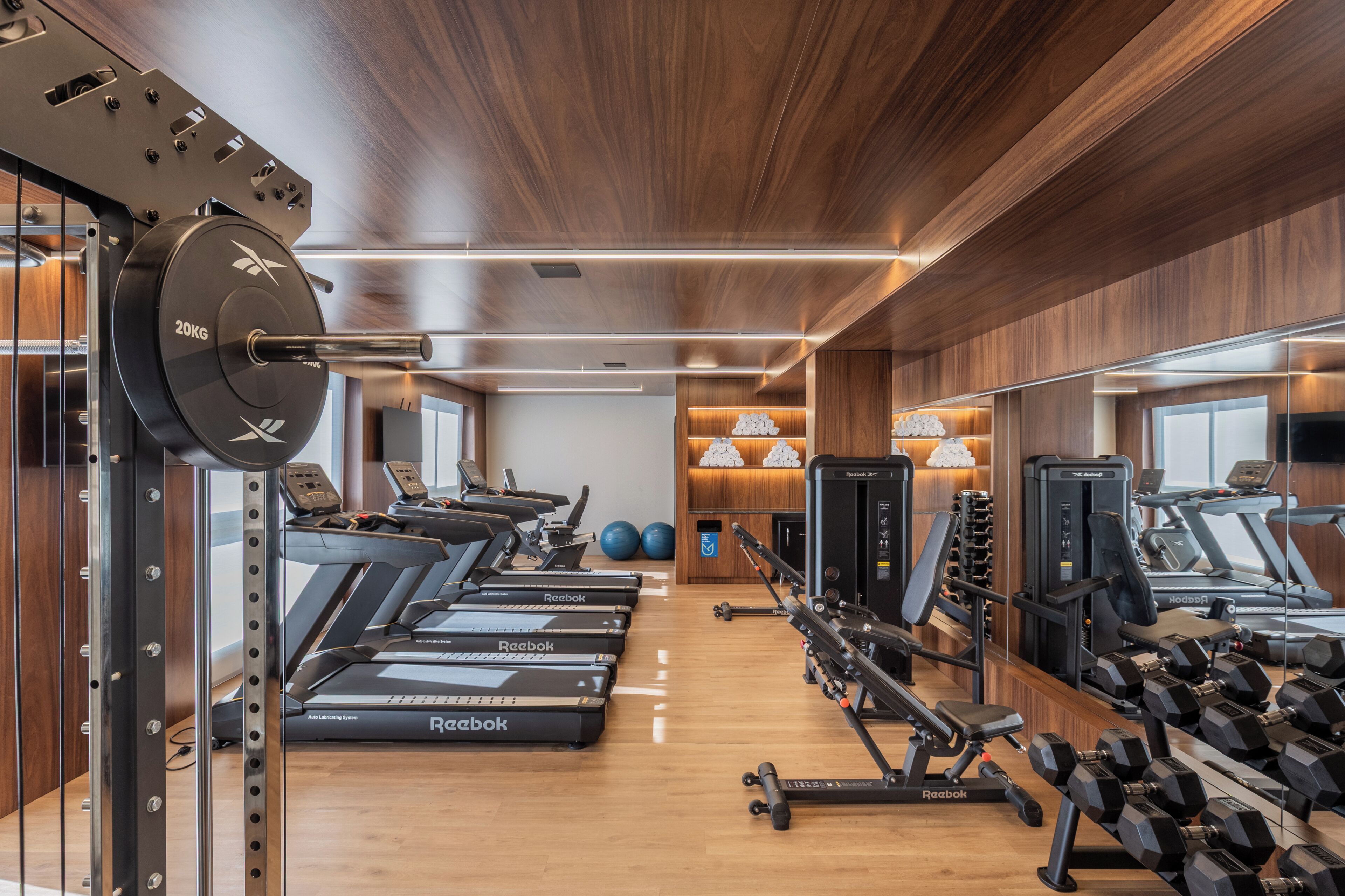 Een fitnessruimte met loopbanden, krachtapparaten en losse gewichten.