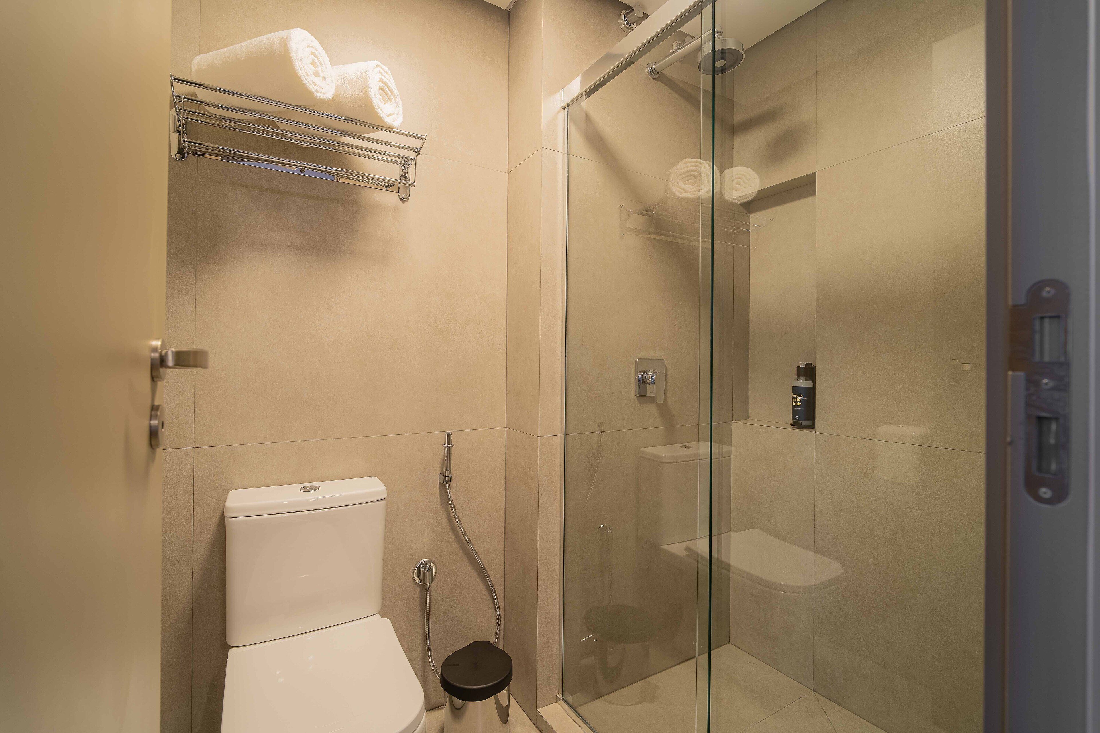 A modern bathroom with a glass shower enclosure, a toilet, and a towel rack.