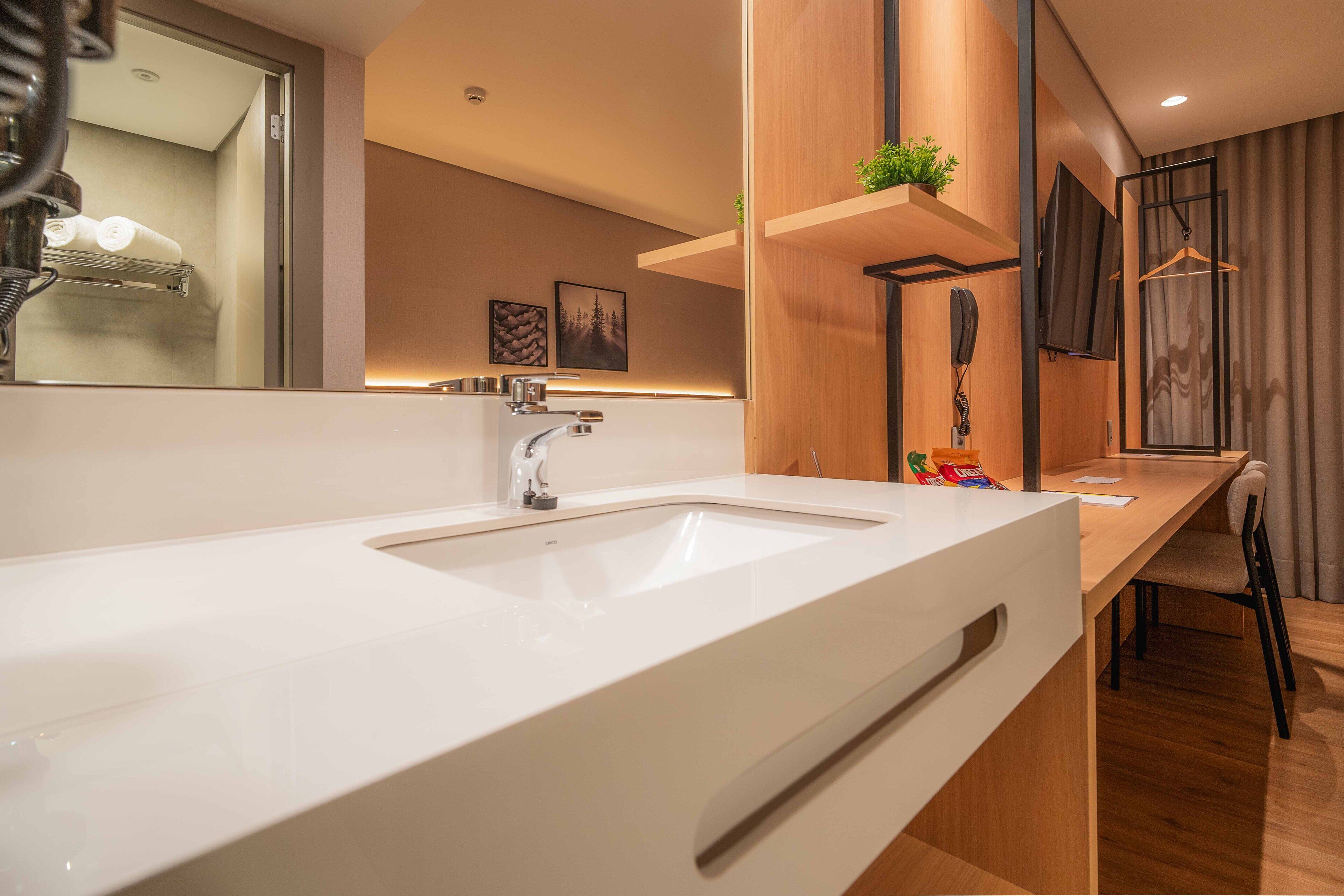 A modern bathroom with a large white sink, a mirror, and a wooden vanity.