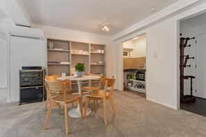 A compact living space with a dining area, built-in shelving, a kitchenette, and a compact entertainment unit.