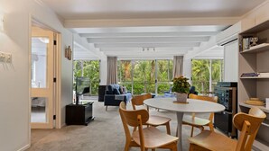 A modern living room with a round table and wooden chairs, a sofa, and a television.