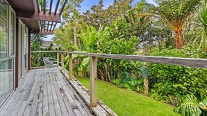 A wooden deck with a railing, surrounded by lush greenery and a variety of tropical plants.