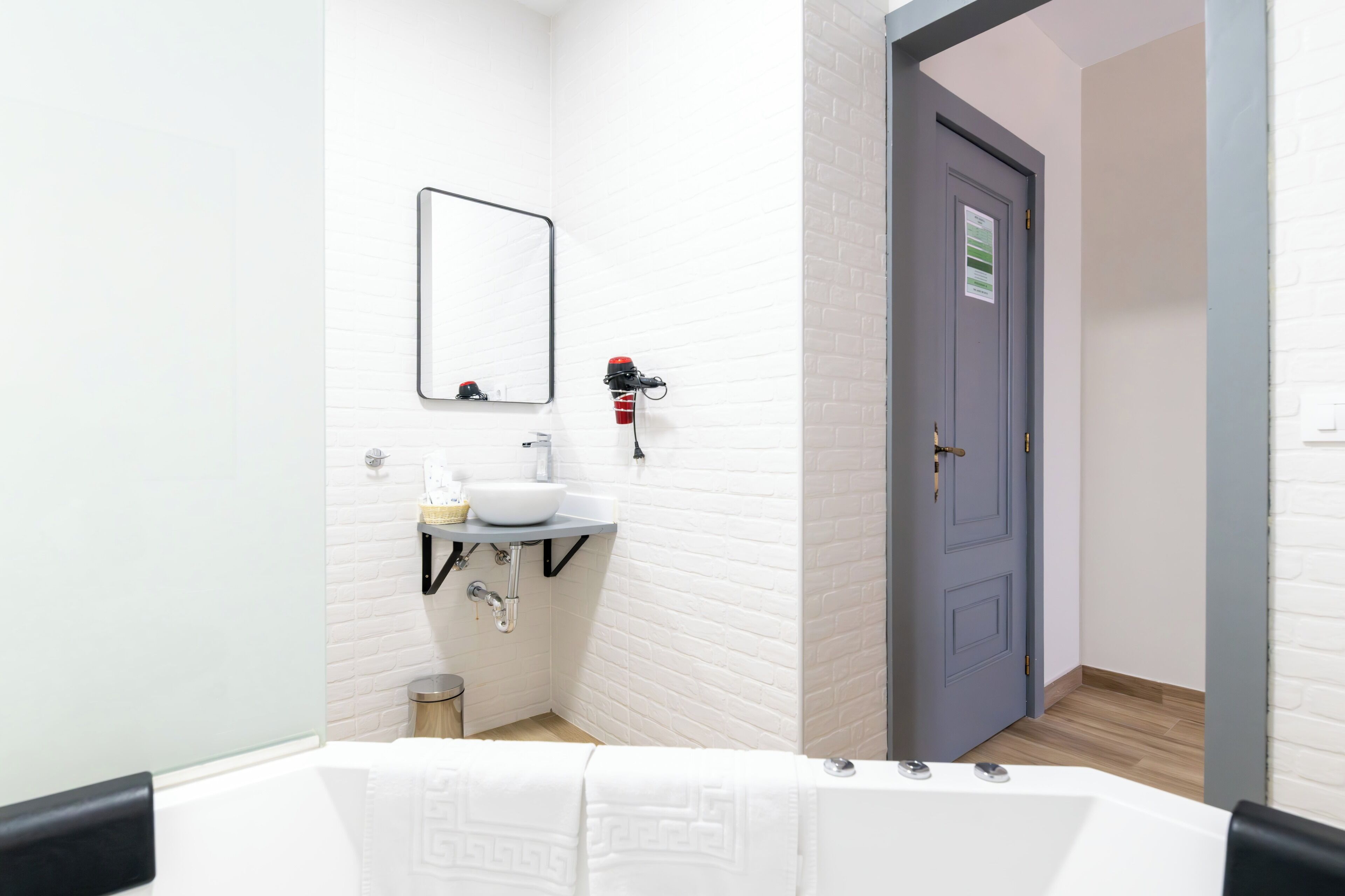 A modern bathroom with a white bathtub, a sink, and a mirror.