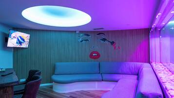 Ein modernes Wohnzimmer mit einer gebogenen Couch, einem Flachbildfernseher und einer einzigartigen Wandkunst-Installation.