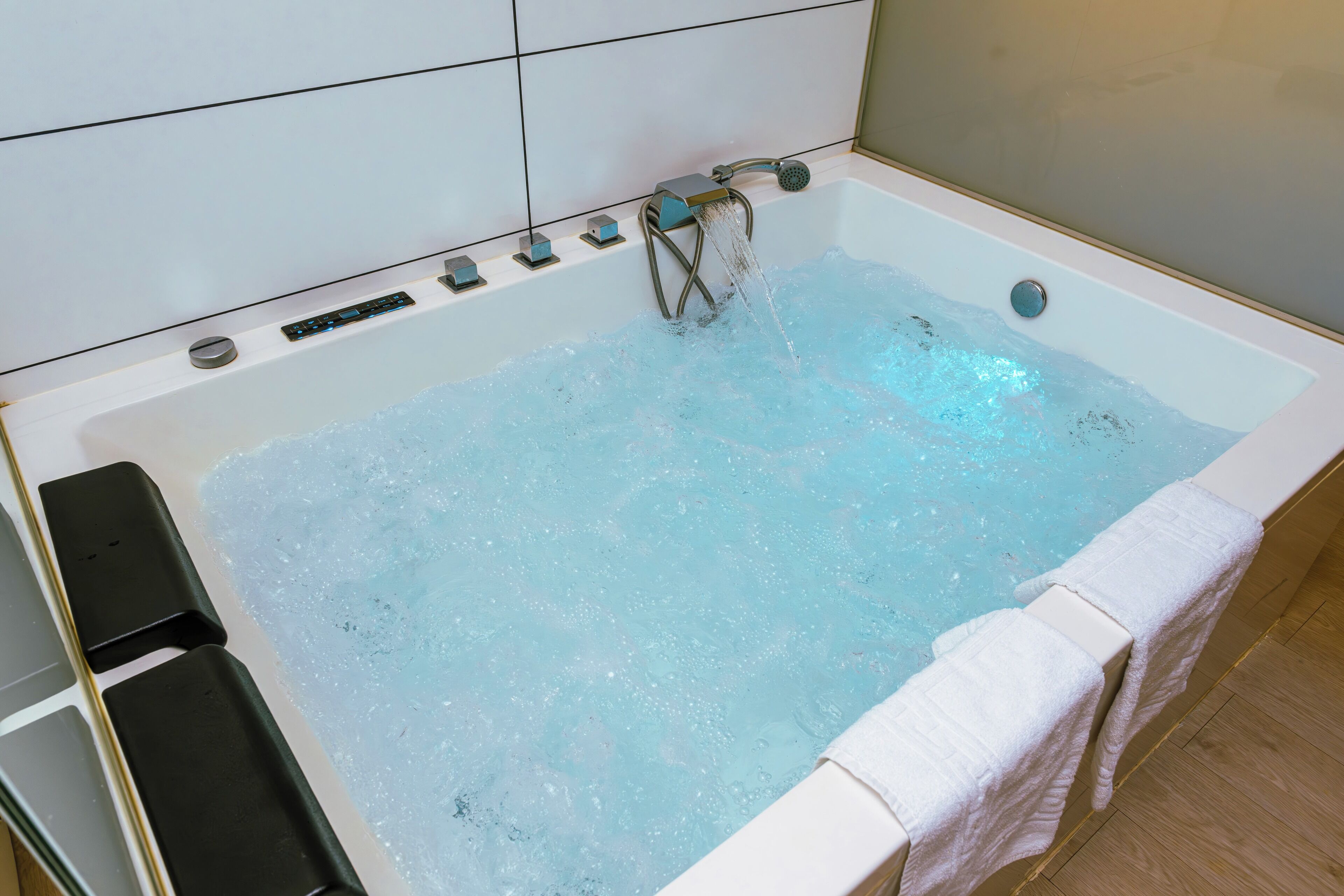 Eine Badewanne mit fließendem Wasser, einer Bedienkonsole und einem Handtuch an der Seite.