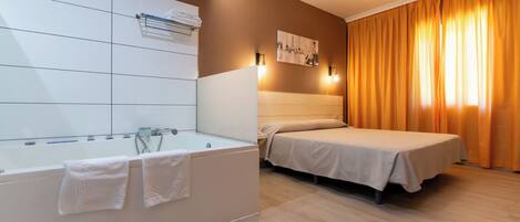 Quarto de hotel moderno com uma banheira grande, uma cama e vista da cidade através das cortinas.