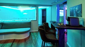 Een moderne kamer met een gebogen zithoek, een bar met krukken, en een groot raam met uitzicht op de oceaan.