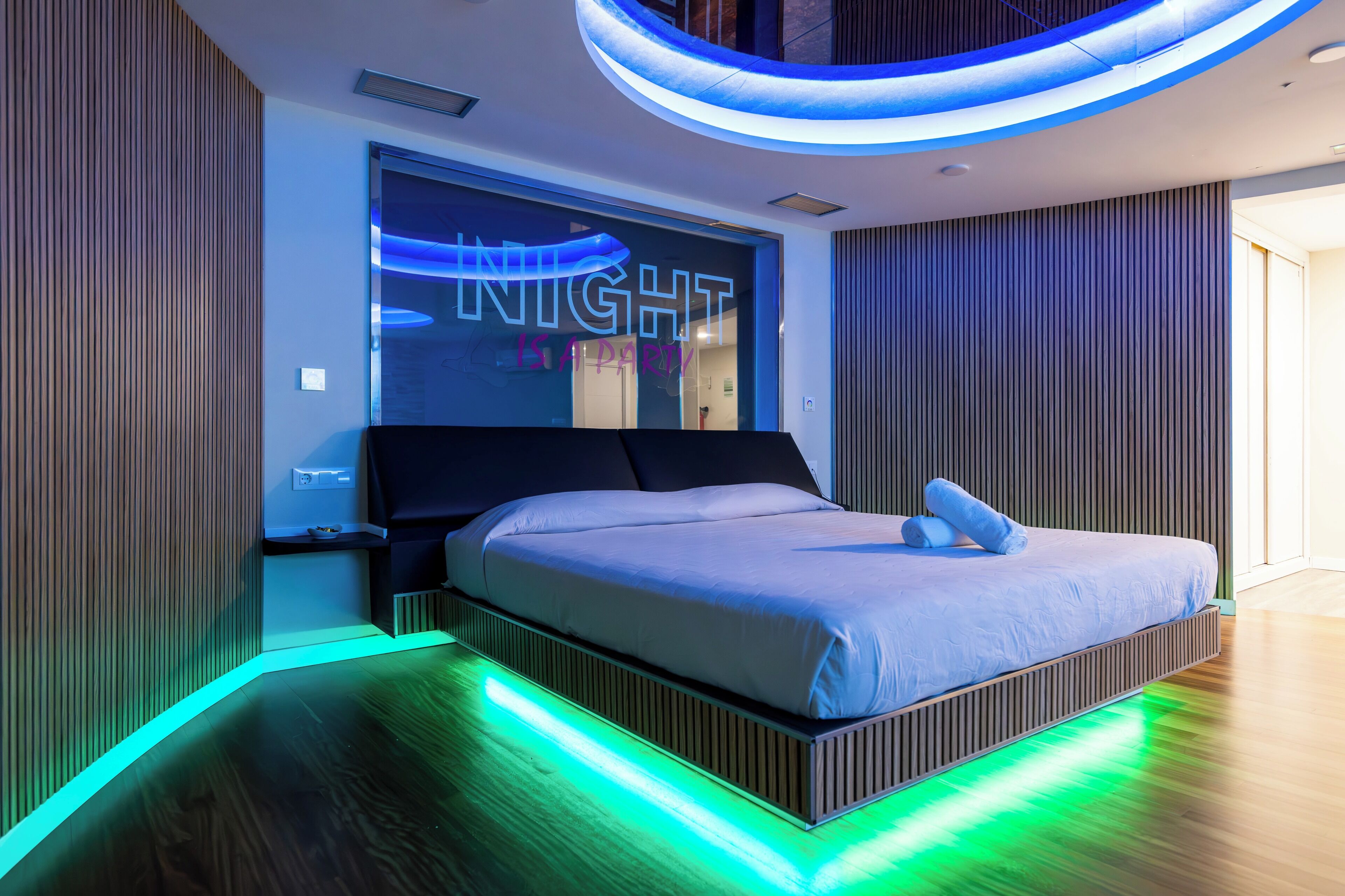 Un dormitorio moderno con una cama, una luz nocturna decorativa y suelo de madera.