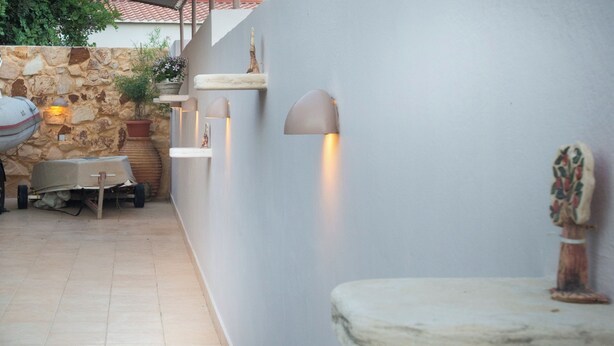 A stone wall with a potted plant and a small table. - Cozy beachside retreat in Kalamaki - steps from the sea (Neo Kalamaki)