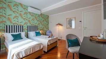 Habitación de hotel con dos camas, un escritorio, una silla, una lámpara y un cuadro en la pared.