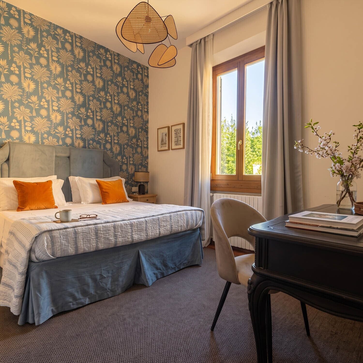 Ein Schlafzimmer mit einem großen Bett, einem Schreibtisch mit Stuhl, einem Fenster mit Vorhängen und einer Wand mit Muster.