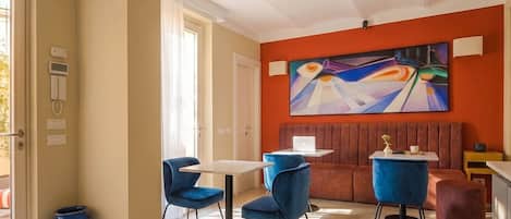 A modern dining area with blue chairs, a white table, and a large abstract painting on the wall.