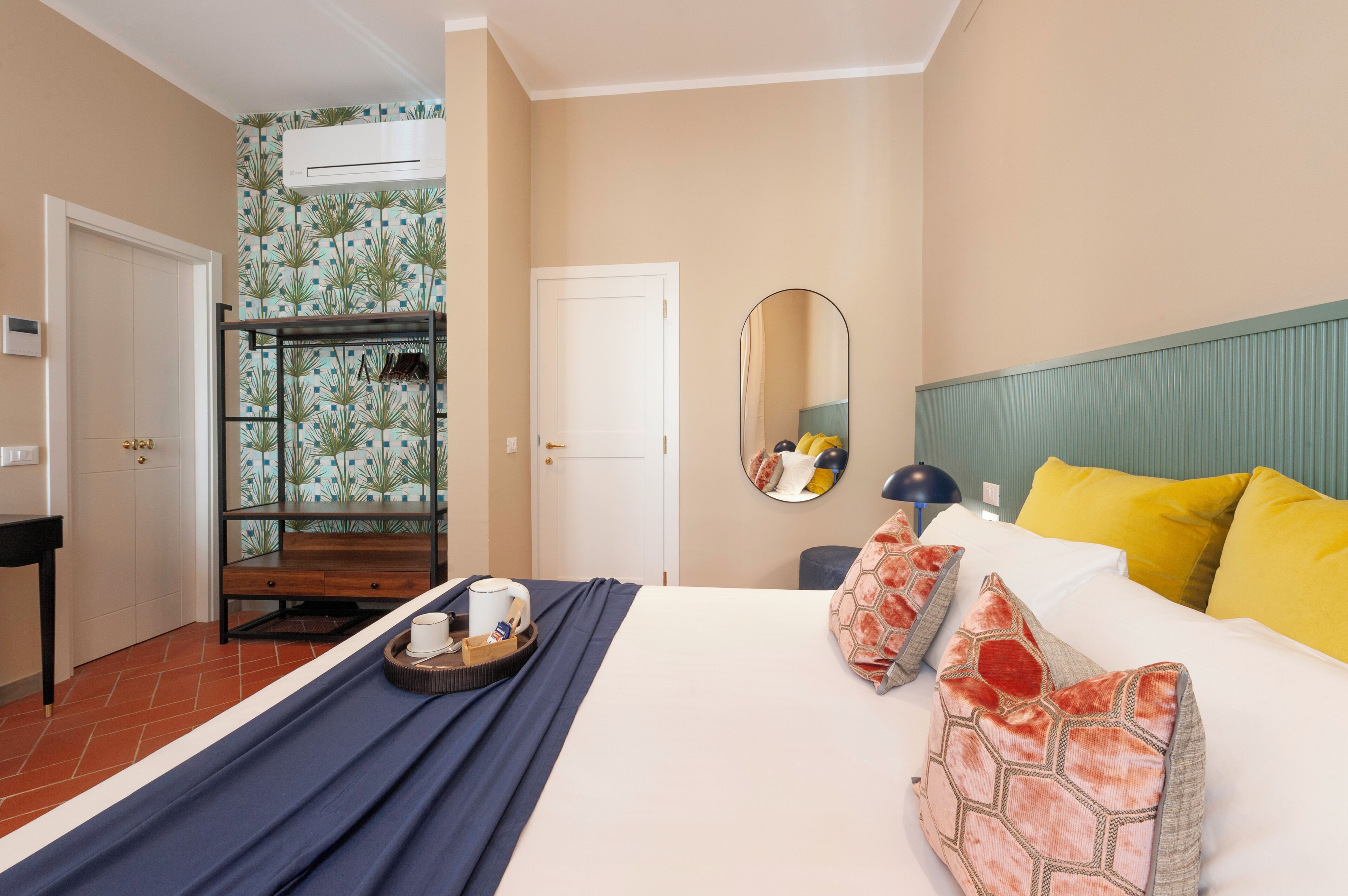 A hotel room with a bed, a bedside table, a mirror, and a wardrobe.