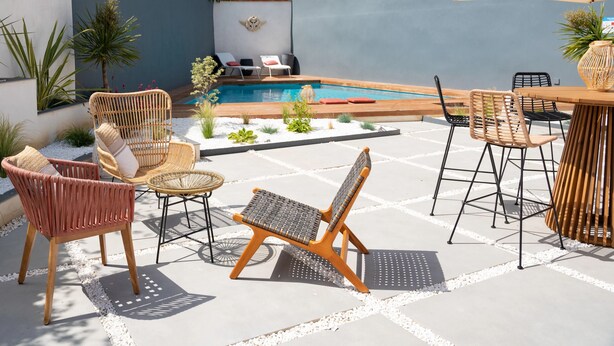 A poolside area with wicker furniture, a pool, and a stone wall. - Hôtel Le Ribéral (Cerbère)