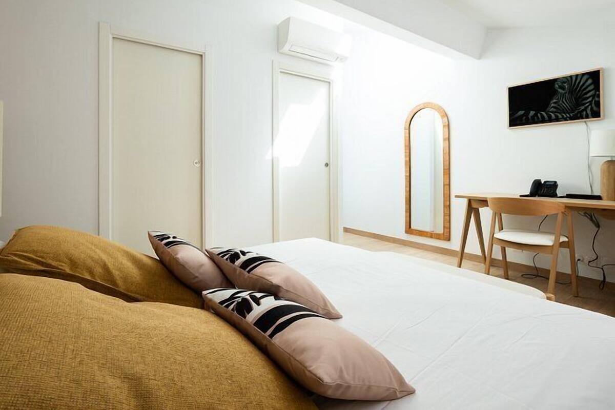 Ein Hotelzimmer mit einem Bett, einem Schreibtisch, einem Sessel, einem Spiegel und einem Bild an der Wand.
