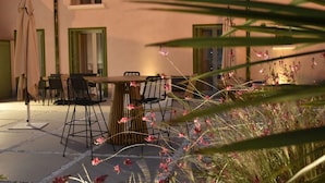 An outdoor patio with a table and chairs, surrounded by plants and flowers. - Hôtel Le Ribéral (Cerbère)