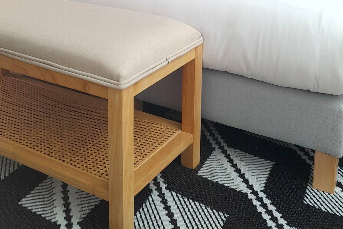 Ein Hotelzimmer mit Bett, Sitzbank, Wandleuchte und Wand mit Muster.