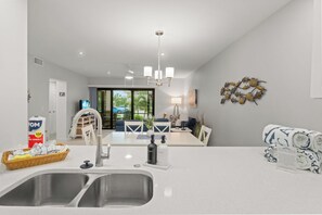 Eine moderne Küche mit einer Spüle, einer Essecke mit Tisch und Stühlen sowie einem Wohnbereich mit einer Couch.