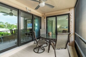 A balcony with a glass door, a ceiling fan, and a table with chairs.