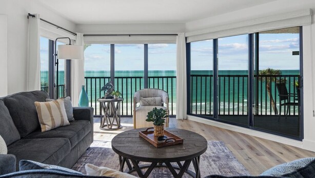 A spacious living room with a large sliding glass door leading to a balcony overlooking the ocean. - Stunning Gulf-Front 3BR Condo with Panoramic Views – Newly Renovated! (Sanibel)