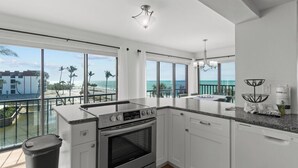 A modern kitchen with a large island, white cabinetry, and a view of the ocean. - Stunning Gulf-Front 3BR Condo with Panoramic Views – Newly Renovated! (Sanibel)