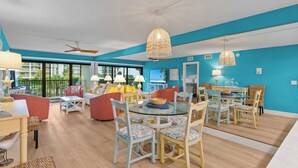 A spacious living area with a dining table, chairs, and a ceiling fan.