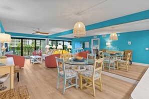 A spacious living area with a dining table, chairs, and a ceiling fan.