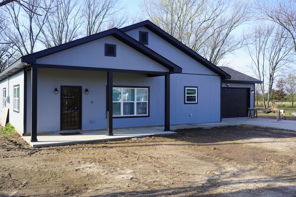 A modern two-story house with a garage, a covered porch, and a well-maintained lawn.