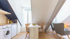 Una cocina con una isla central, sillas de madera, una lavadora y un ventanal con cortinas.
