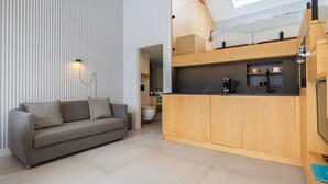 Een moderne woonruimte met een bank, een keukenhoek en uitzicht op de badkamer.