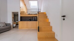 Een modern interieur met een houten trap, een keukenhoek en een zithoek.