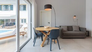 Relax in this stylish living space with a dining area, sofa, and floor lamp, offering a view of the outdoor pool.
